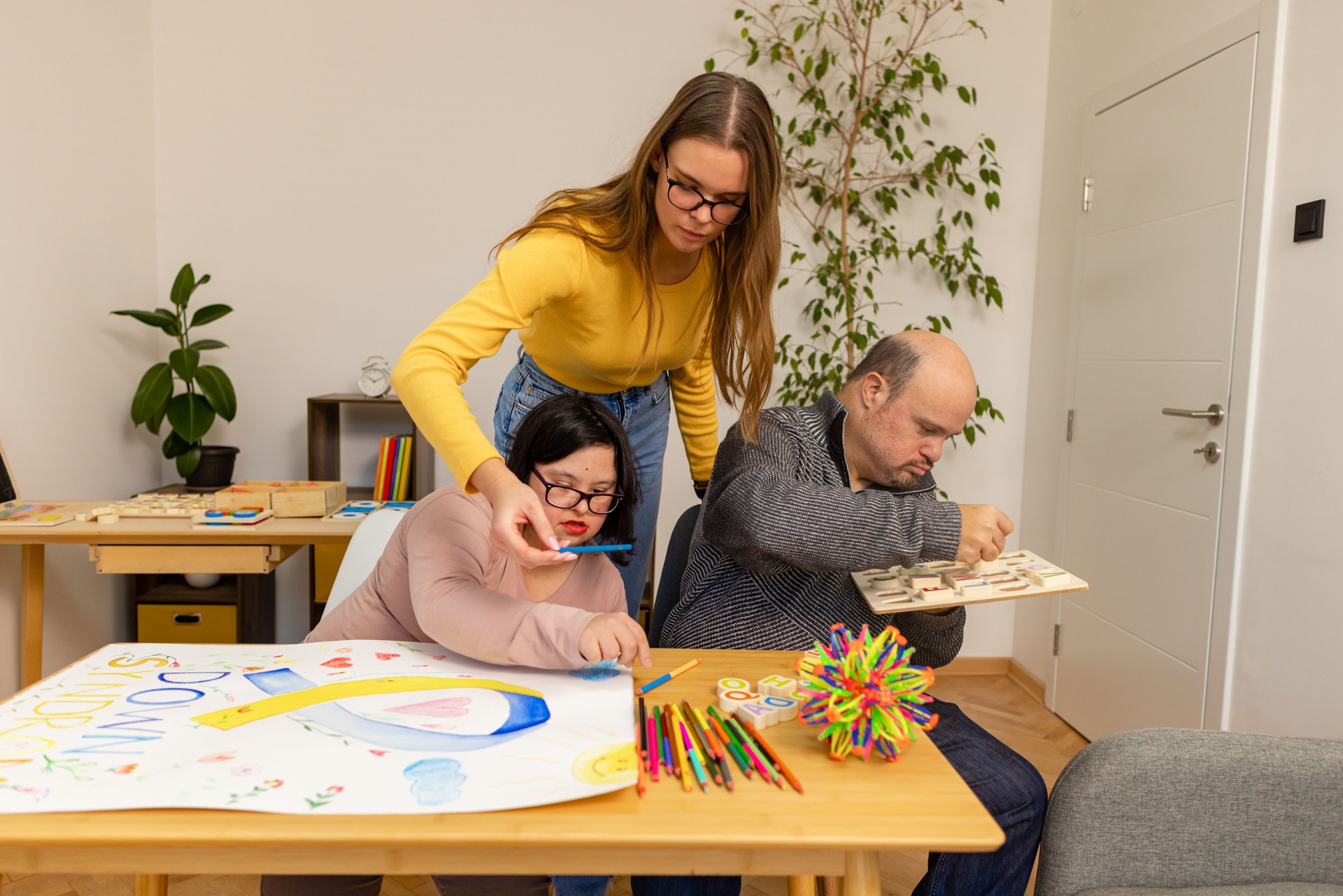 Assistant gently guiding a man and woman  with Down syndrome