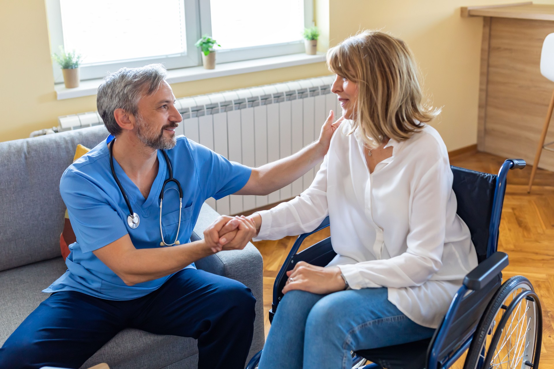 Careful Doctor is Talking with Disabled Mature Woman in a Wheelchair and Giving her bits of Advice.