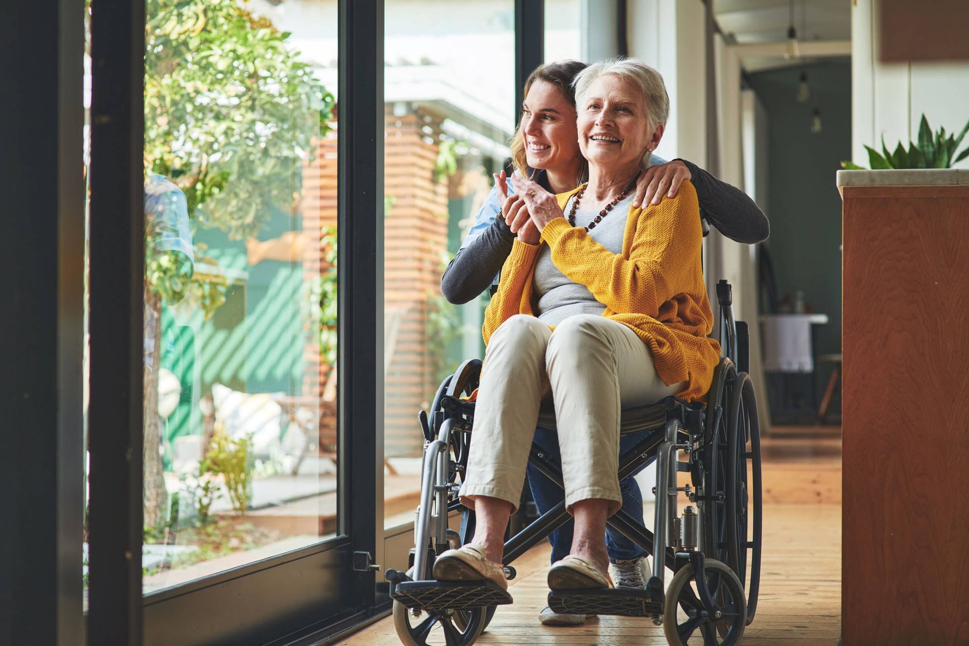 Shot of a young nurse caring for a senior woman in a wheelchair in a retirement home
